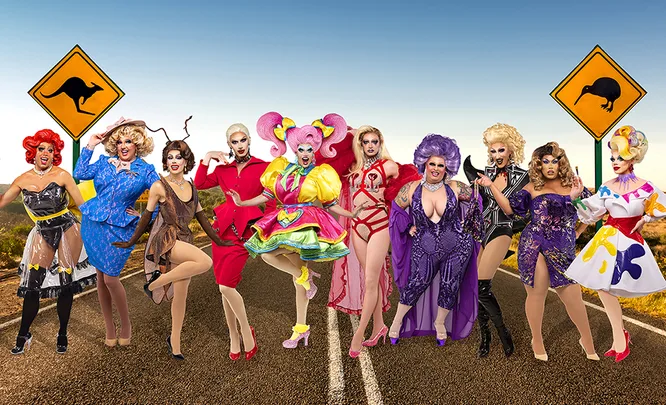 Ten drag queens in colorful outfits pose on an Australian road with kangaroo and kiwi signs in the background.