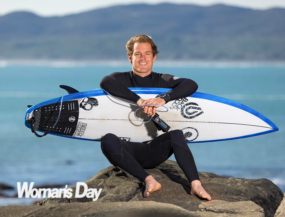 Billy Stairmand Sitting on a rock holding his surfboard