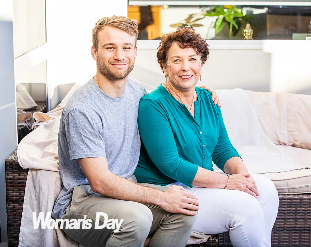 A young man and an older woman sitting on a sofa, smiling, with "Woman's Day" logo in the corner.