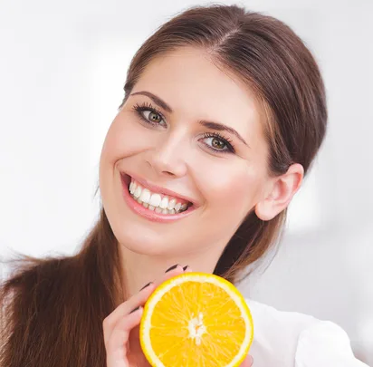 Smiling woman holding a sliced orange in her hand.