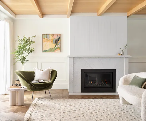 Modern living room with green chair, fireplace, abstract painting, and light wood accents.
