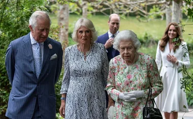 Group of formally dressed people walking outdoors in a garden setting.