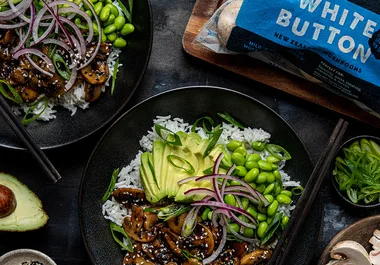 Bowl with rice, avocado, edamame, mushrooms, red onion, and sesame seeds. Package labeled "White Button Mushrooms" visible.