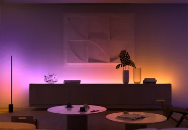Ambiently lit modern living room with abstract art, round tables, and decorations on a sideboard.