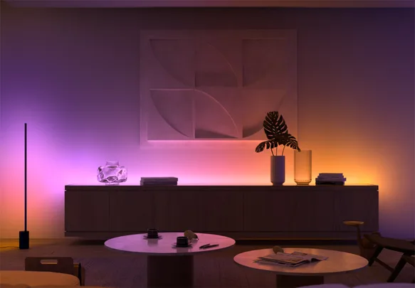 Ambiently lit modern living room with abstract art, round tables, and decorations on a sideboard.