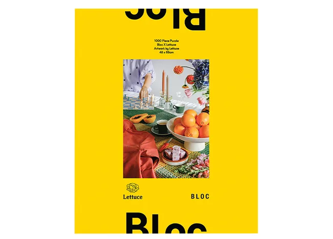 Puzzle box cover with a vibrant table setting featuring oranges, candles, and decorative items on a yellow background.