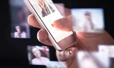 A hand swiping on a smartphone screen with blurred images, suggesting browsing or selecting photos in an app.