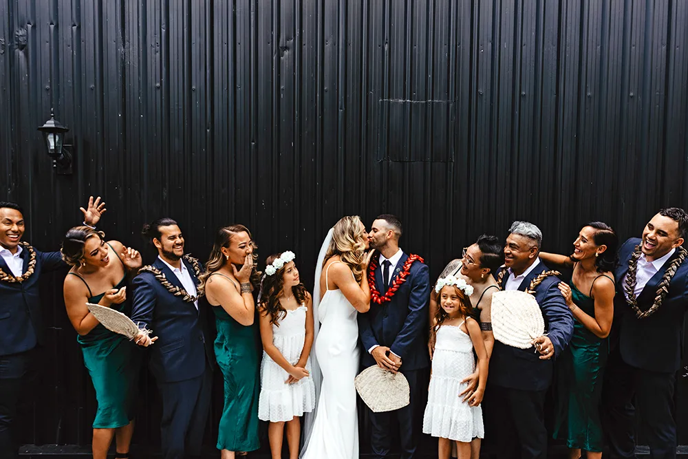 Niall and Tamāli'i kissing, surrounded by their bridal party on their wedding day