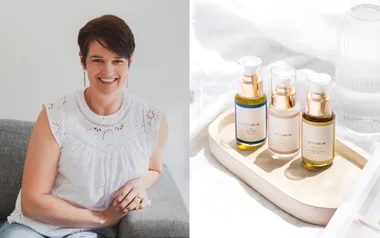 Woman smiling on a couch; three LOVESKIN skincare bottles on a tray beside her.