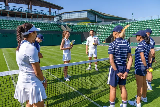 Tennis players and officials on a green court preparing for a match at an outdoor stadium.