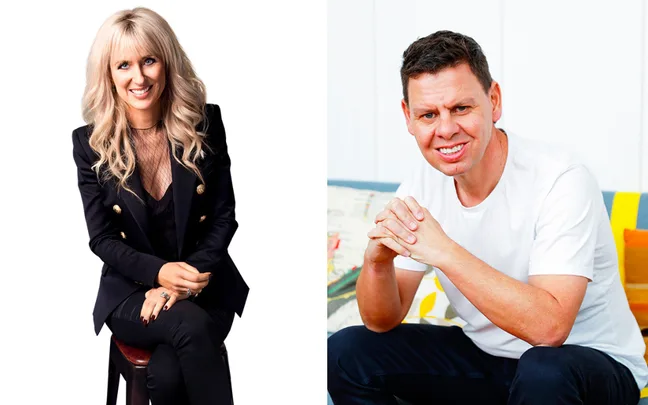 Two people seated: one with long blonde hair in a black outfit, the other with short brown hair in a white t-shirt.