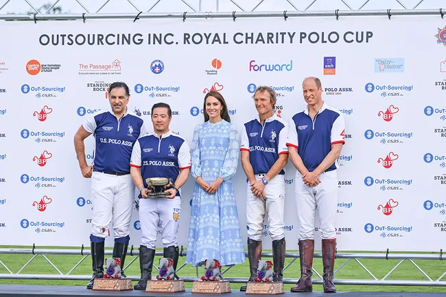 Polo team poses with woman at Royal Charity Polo Cup; three hold trophies.