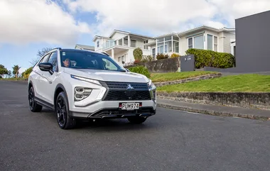 White Mitsubishi Eclipse Cross parked on a suburban street with modern homes in the background.