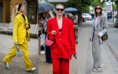 Stylish women in oversized suits: one in yellow, one in red, and one in gray, walking on a city street.