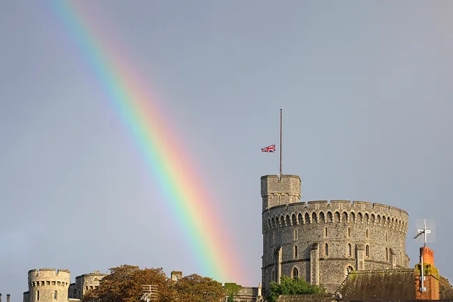 Rainbow over Windsor Castle, with the Union Jack at half-mast on a cloudy day.