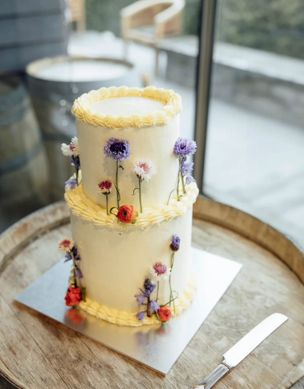 A white wedding cake with colourful flowers climbing up the sides