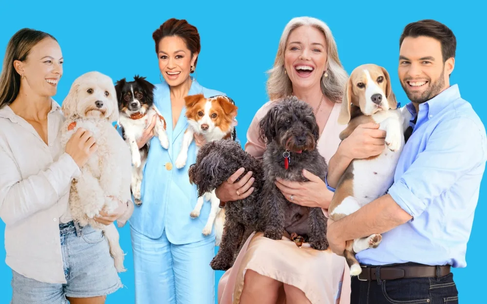Group of five smiling people holding dogs against a blue background.