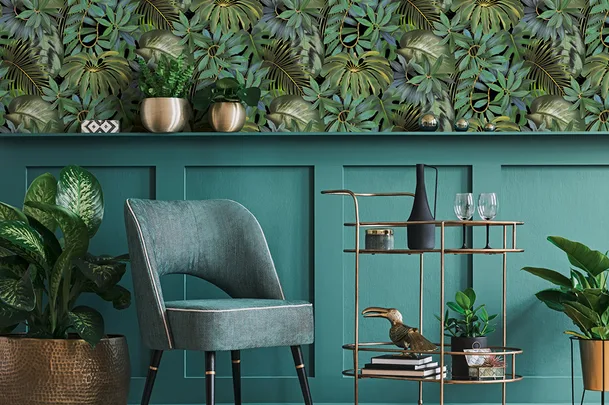 Cozy room with green chair, tropical wallpaper, plants, and a gold bar cart holding decor and glasses.