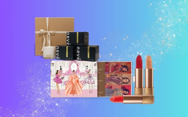 Gift set with candles, skincare boxes, illustrated card, and red and nude lipsticks on a blue gradient background.