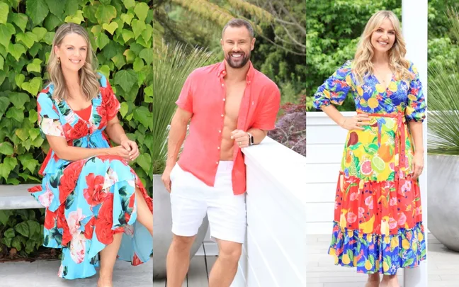 Three people in colorful summer outfits pose outdoors in front of greenery.