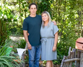 Couple standing in a lush green garden, smiling and posing for a photo.