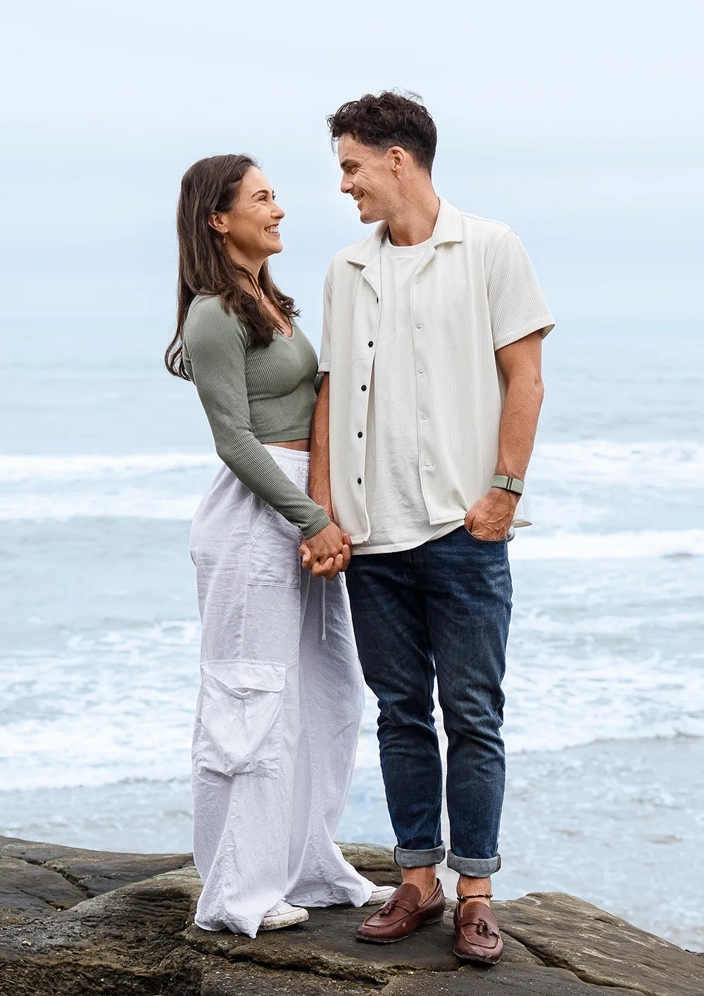 Paul Coll and fiancé Nele Gilis standing on a rock in front of the ocean