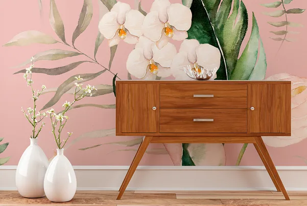 Mid-century modern wooden console against pink floral wallpaper with two white vases holding flowers.