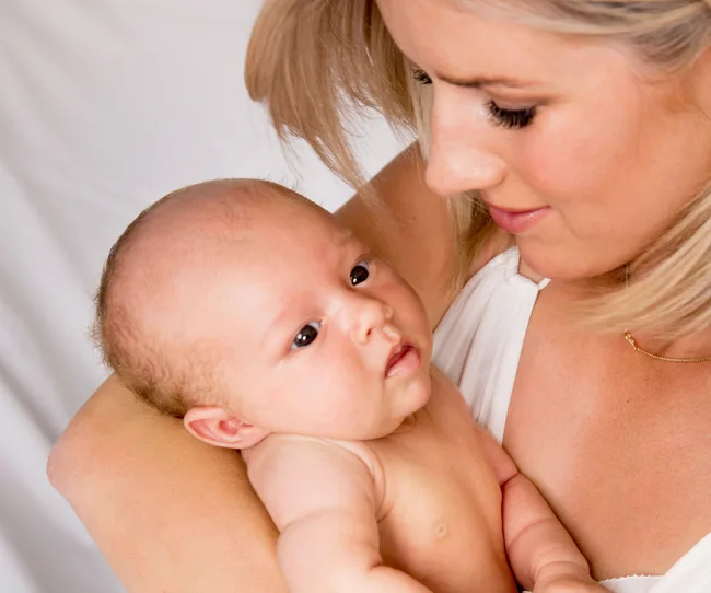 Mother holding a baby closely, looking at each other lovingly.