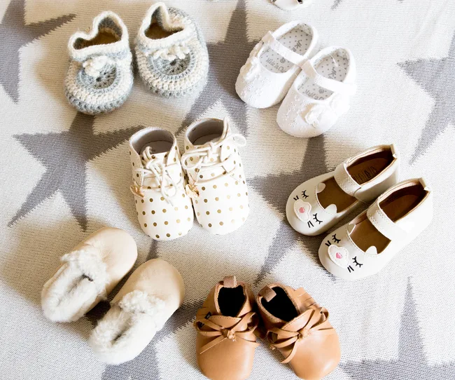 Assorted baby shoes in various styles and colors on a star-patterned background.