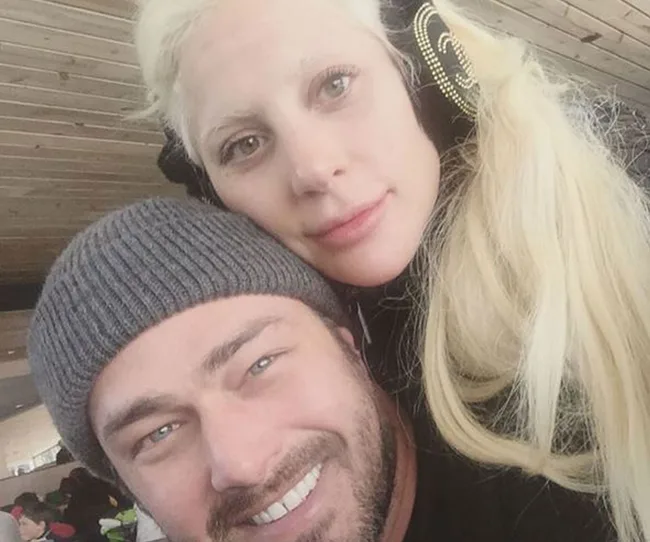 A man in a grey beanie and a woman with long blonde hair smiling closely together.