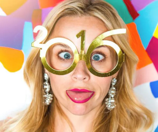 Person wearing 2016 glasses with a playful expression against a colorful background.