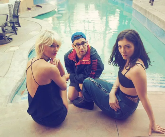 Three people sitting beside a swimming pool, two women and a man in casual attire, relaxed and looking at the camera.