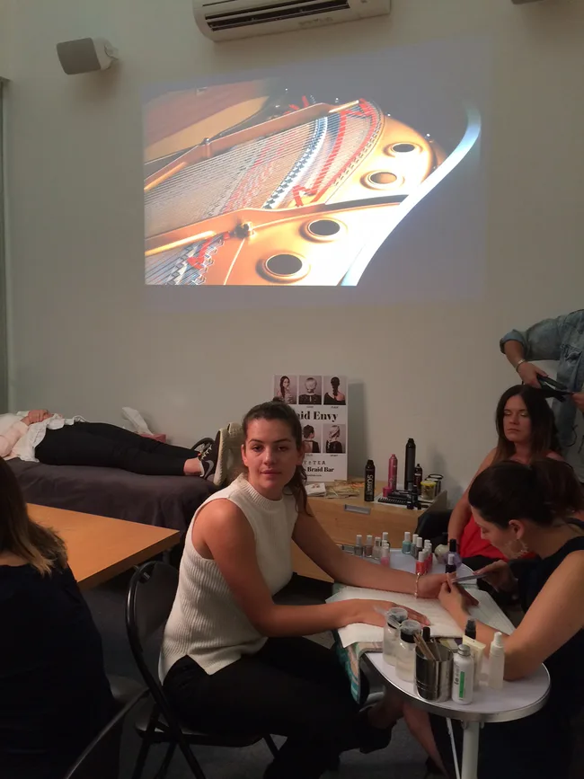 A woman getting a manicure at a salon with a piano image projected on the wall.