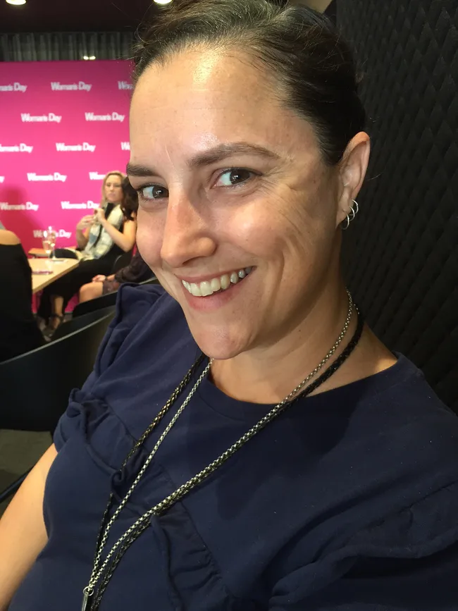 Woman smiling at "Women&rsquo;s Day" event with pink background.