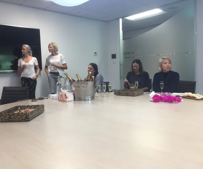 A group of people in a conference room with champagne and snacks on the table.