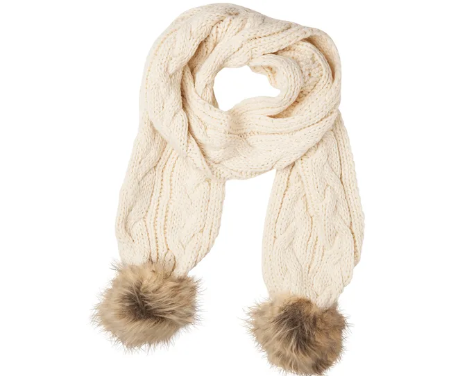 Cream knitted scarf with cable pattern and fluffy pom-poms on both ends against a white background.