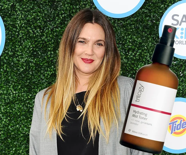 Woman smiling against greenery background with a floating bottle of Trilogy Hydrating Mist Toner in the foreground.