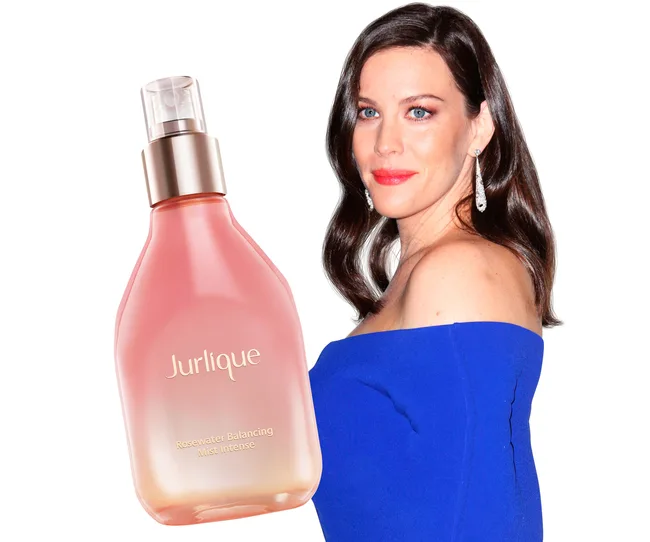 Woman in blue dress with Jurlique Rosewater Balancing Mist bottle.