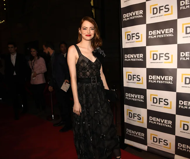 Actress in a black dress on the Denver Film Festival red carpet, smiling beside the DFS banner.