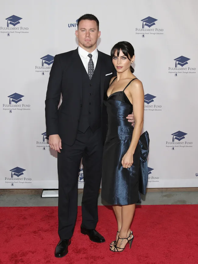 Man in a suit and woman in a blue dress pose on red carpet at Fulfillment Fund event.