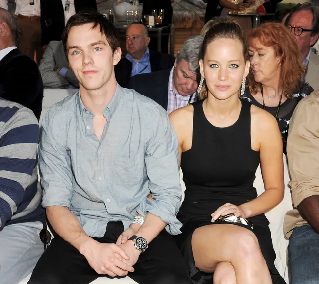 A man and a woman sitting together at an event, surrounded by other attendees.