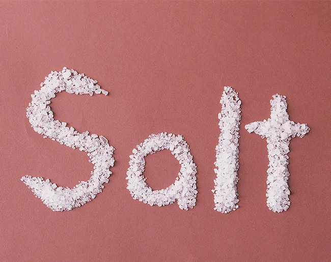 "Crystals of salt forming the word 'Salt' on a maroon background."