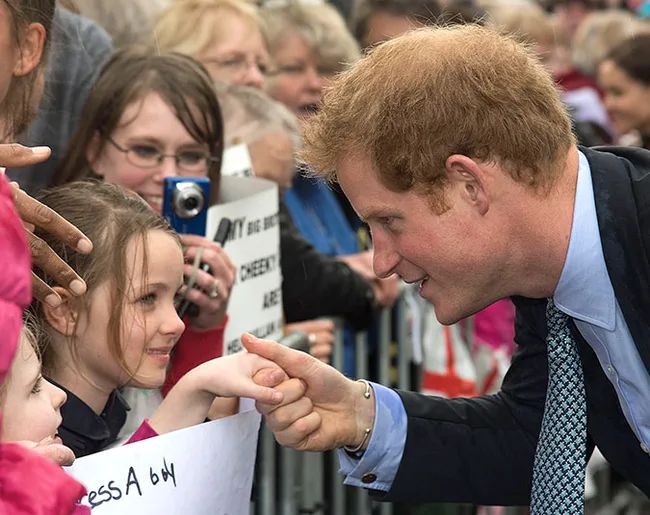 Person greeting a child in a crowd, smiling and holding her hand.