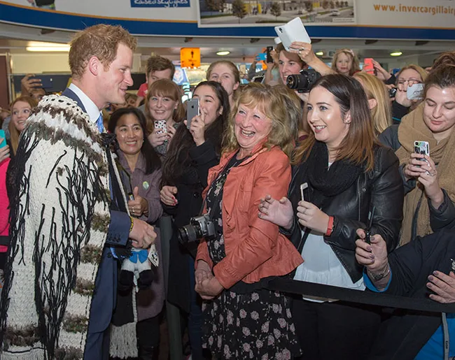 Group of people smiling and taking photos with a man in traditional attire at an event.