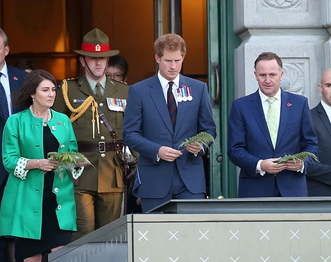 A group of people, including a man in a military uniform, holding leaves at an outdoor event.