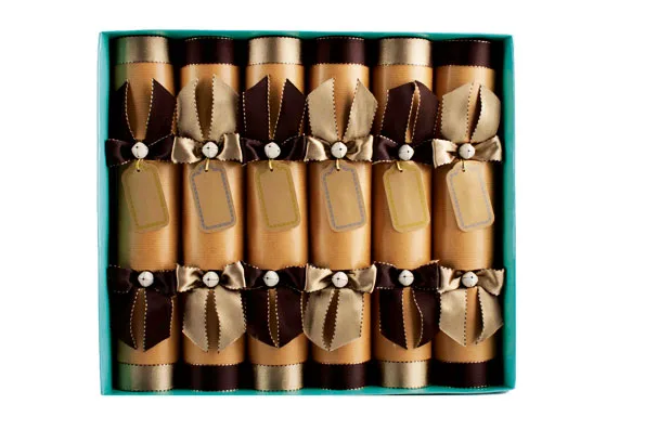 Box of eight golden and brown holiday crackers, each tied with ribbon and tag, in a turquoise box.