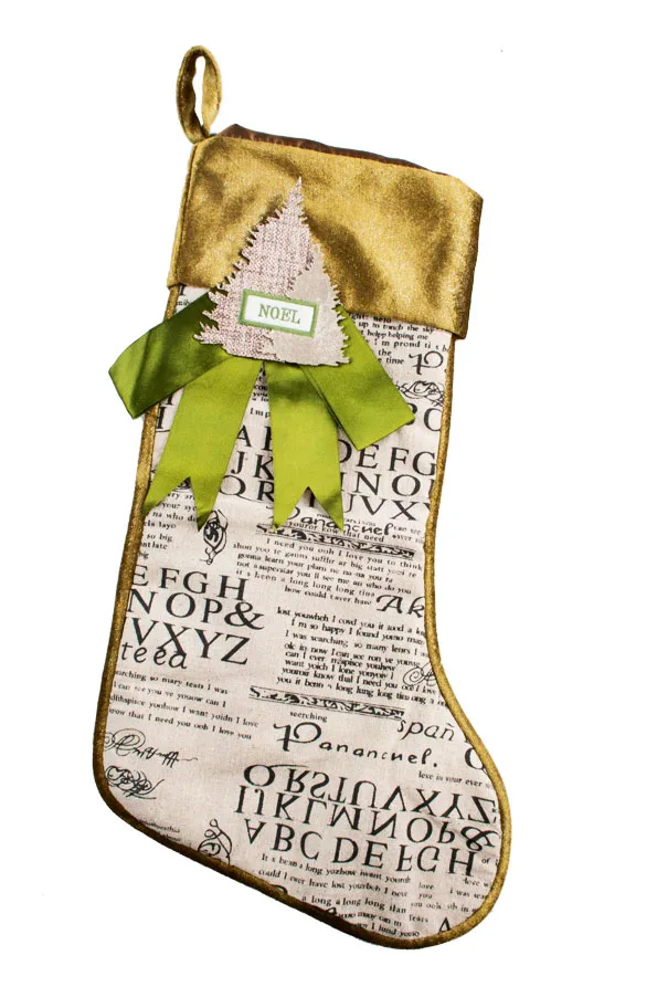 Christmas stocking with gold trim, alphabet print, and green bow with "Noel" on a fabric tree detail.