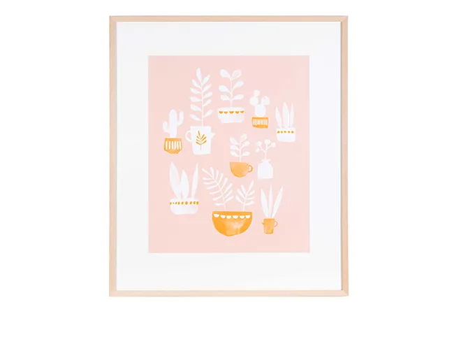 Framed artwork with minimalist plant illustrations in white and yellow on a pink background.