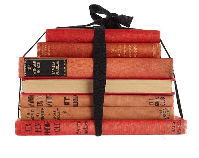 Stack of vintage red books tied with a black ribbon, with visible titles like "The Winged Horse" and "Finding Out."