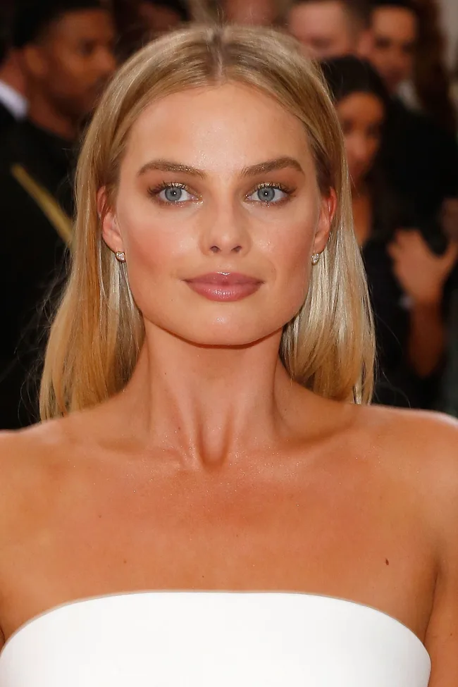 A woman with long blonde hair and blue eyes in strapless white attire at a formal event.